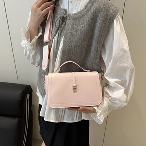 Elegante borsa sottobraccio rosa chiaro con chiusura dorata e tracolla su modella