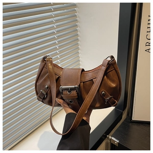 Close-up of vintage brown pleated leather shoulder bag with wide metal buckle and rivets