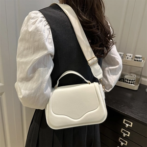 Chic off-white faux leather saddle bag with wave-edge flap and wide fabric strap