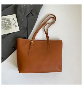 Sac cabas en similicuir marron présenté avec un blazer gris dans un décor minimaliste