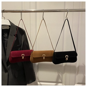 Close-up of suede underarm bags in burgundy, brown and black with gold metal U-locks