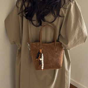Brown retro leather bucket bag with top handles and colorful beaded charm accessory