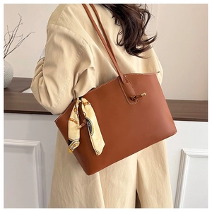 Close-up of caramel leather tote bag with printed silk scarf on a model's shoulder