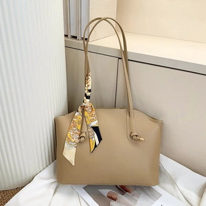 Detail of a minimalist khaki leather tote bag with a decorative silk scarf on a magazine