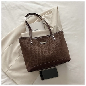 Détail du sac cabas léopard avec base en cuir marron et plaque de mode métallique