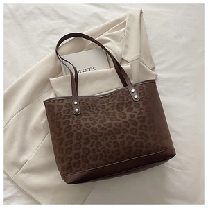 Vue détaillée du sac cabas léopard avec bordures en cuir marron et rivets dorés