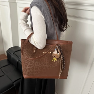 Chic leopard print tote bag with plush bear charm and metallic fashion logo plate
