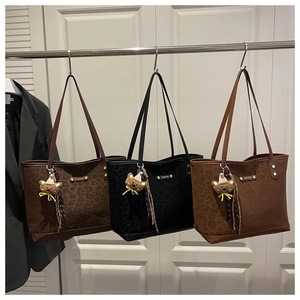 Dettaglio di borse tote leopardate in tre colori con ciondoli a forma di orso e logo metallico