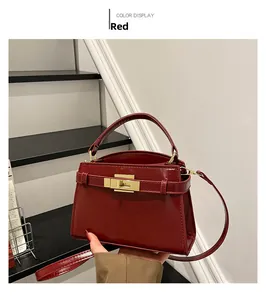 Detail view of red glossy crocodile pattern bag with iconic gold hardware and top handle