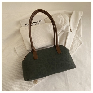 Dettaglio della borsa verde scuro con trama leopardata su sfondo in velluto a coste