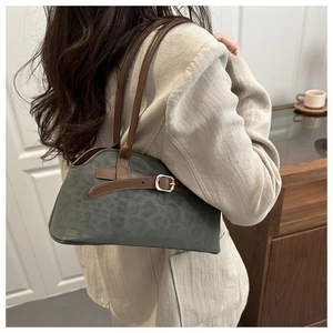 Detail of dark green leopard print suede baguette bag showing side view on a shoulder