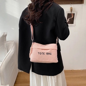 Pink corduroy tote bag with TOTE BAG embroidery and side charm on model shoulder