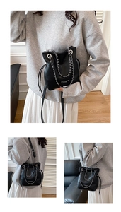 Detailed view of black bucket bag with silver chain strap and drawstring closure