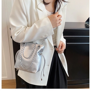 Detail of silver metallic bucket bag with chunky chain strap and drawstring closure