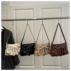 Detail of four colorful bow shoulder bags with star rivets on a metal rack display