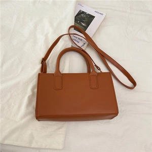 Detail of caramel brown leather handbag with round handle on a minimalist background
