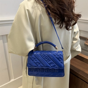 Blue embossed fashion handbag with adjustable shoulder strap shown on a model