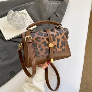 Brown leopard print crossbody bag with gold hardware and top handle in a lifestyle setting