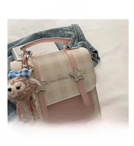Detail of pink and beige plaid texture handbag with star charms and plush bear pendant