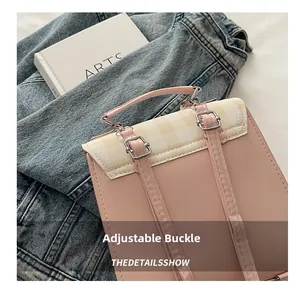Close-up of adjustable silver metal buckle on a pink leather and checkered backpack