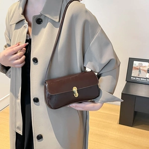 Retro dark brown baguette bag with golden buckle shown as a stylish underarm shoulder bag