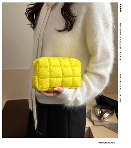 Detail of yellow quilted square clutch showing puffy texture and soft nylon fabric