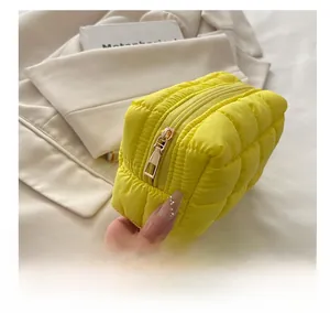 Detail view of the smooth golden metal zipper on a bright yellow quilted puffer bag