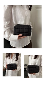 Detail of black quilted puffer cosmetic bag with smooth zipper and minimalist texture