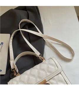 Detail view of white quilted shoulder bag with gold clasp and smooth faux leather texture