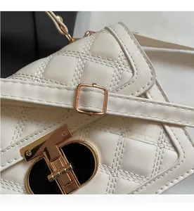 Close-up of white quilted leather texture and gold metal buckle on a square handbag