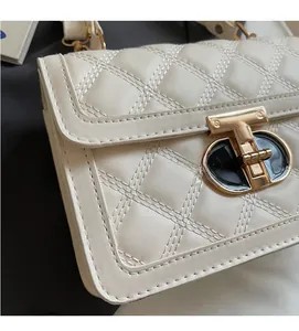 Close-up of the beige quilted crossbody bag featuring a golden T-shaped twist lock buckle