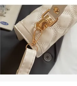 Detail of durable gold-tone metal hook and stitching on beige quilted leather bag