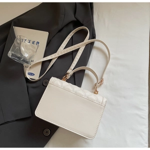 Macro shot of cream white crossbody bag with quilted heart pattern and gold hardware