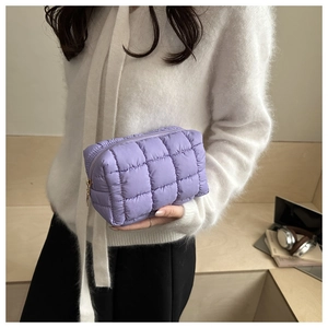 Detail of purple quilted padded handbag with metallic zipper and glossy nylon texture