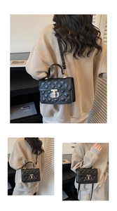 Detail of black quilted leather handbag with gold metal clasp and versatile shoulder strap