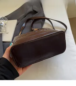 Detailed macro view of dark brown faux leather bag with smooth finish and gold metal buckle