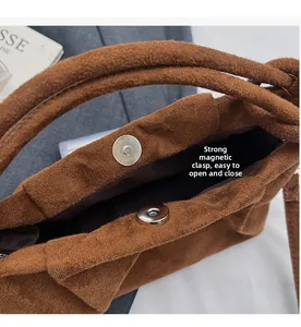 Detail shot of the strong magnetic silver buckle closure on a brown suede handbag