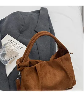 Close-up of caramel suede cloud bag with soft wide handles and elegant pleated texture