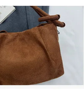 Detailed close-up showing the suede texture and knot design of the brown shoulder bag