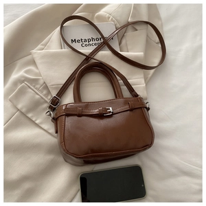 Brown vintage PU leather tote bag with metal buckle on a stylish blazer background