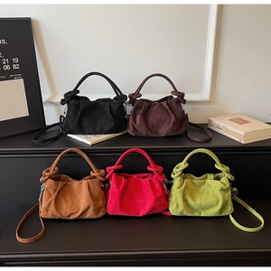 Detail of colorful suede dumpling bags with knotted handles and thin leather straps