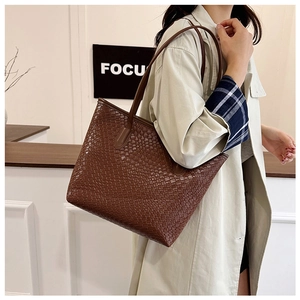Detail of the brown woven texture and dual straps on a large crossbody tote bag
