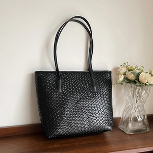 Close-up of premium black woven texture and refined craftsmanship on a large tote bag
