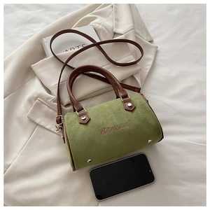 Overhead view of green suede Boston bag with brown leather handles and brand embroidery