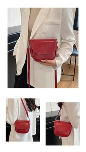 Dettaglio della borsa a tracolla in pelle rossa con fibbie argentate sul blazer