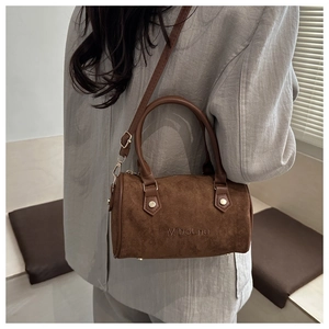 Detail of brown suede Boston bag showing the embossed brand logo and soft leather texture