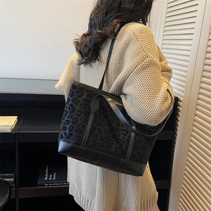 Minimalist black leopard print tote bag with leather straps worn by a female model