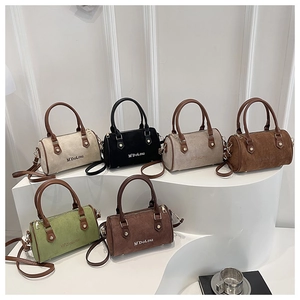 Detail view of retro suede Boston bags in six colors displayed on a white podium