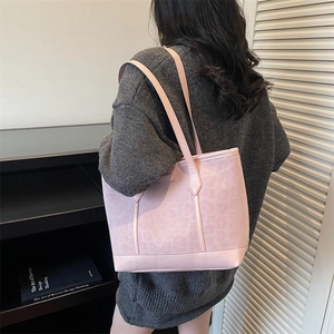 Pink leopard embossed tote bag with long shoulder straps shown on a model