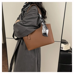 Detail view of large caramel brown leather tote bag with a geometric pattern scarf accent